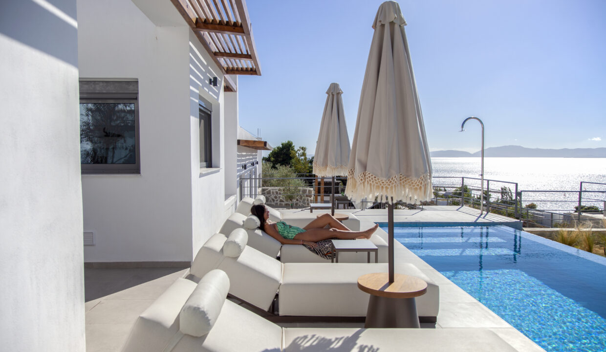 villa-empeiria-paleros-greece-girl-laying-on-sunbed-next-to-swimmingpool-with-view-on-the-sea